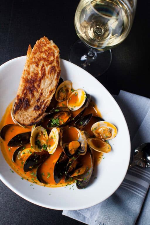 Seafood stew with bread and white wine glass.