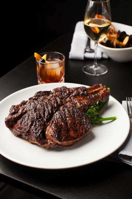Grilled steak with drinks on a restaurant table.