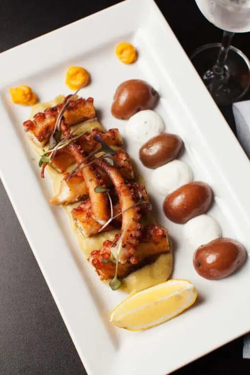 Grilled octopus dish with potatoes and sauce.