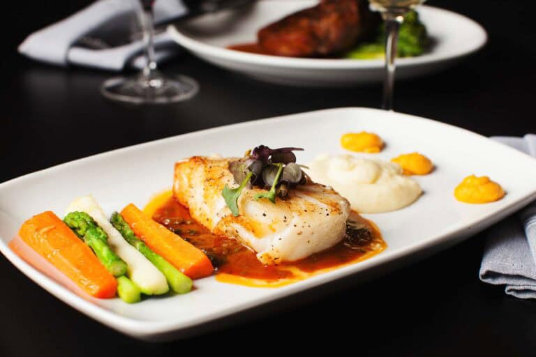 Gourmet fish dish with vegetables and sauces.