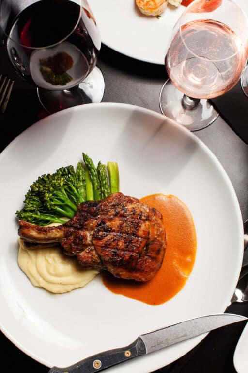 Steak with mashed potatoes and asparagus, wine glasses.
