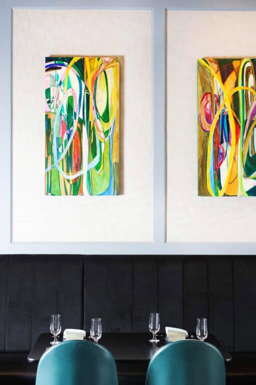 Colorful abstract paintings above modern dining table setting.
