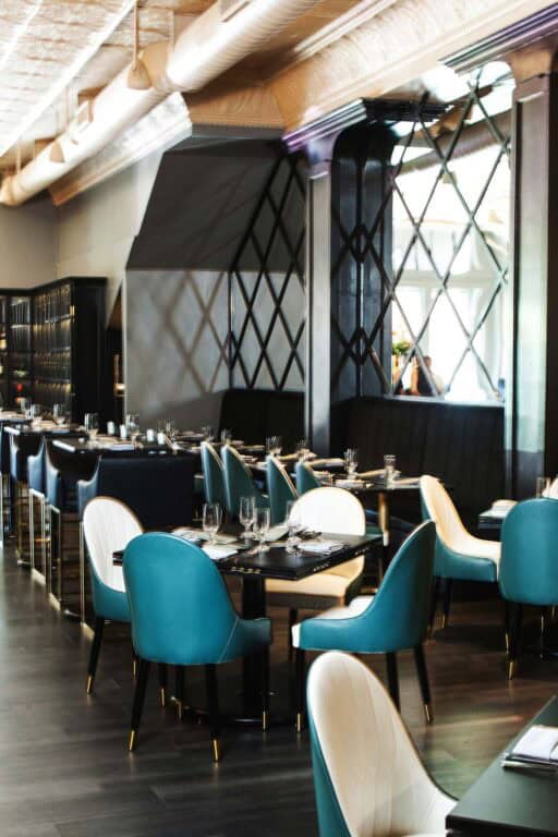 Modern restaurant interior with teal and white chairs.