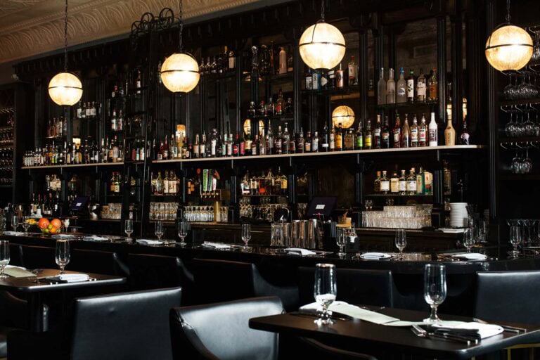 Cozy bar interior with shelves of liquor bottles.